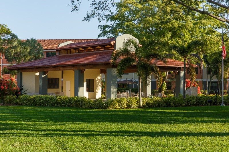 A building surrounded by lush greenery and trees under a clear sky.