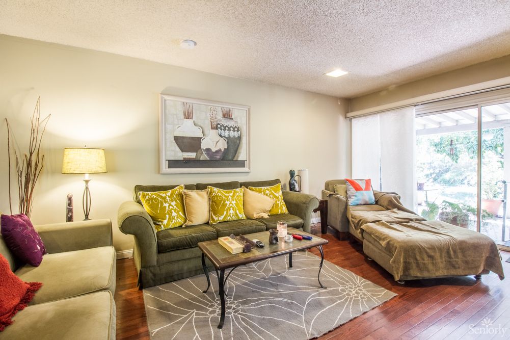 A cozy living room with a green sofa, armchair, coffee table, and modern decor.