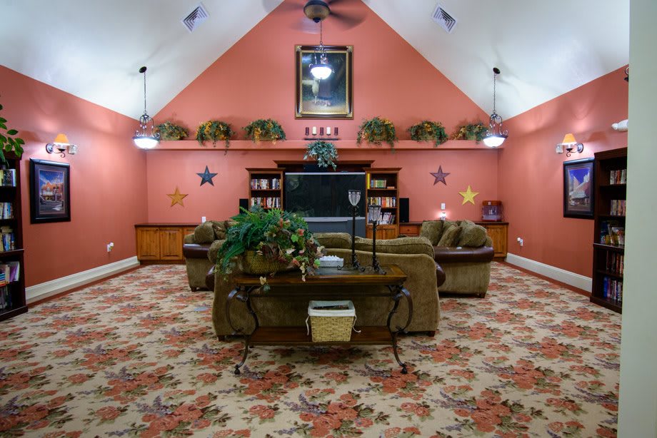 A cozy living room with a large television, comfortable sofas, and decorative plants.