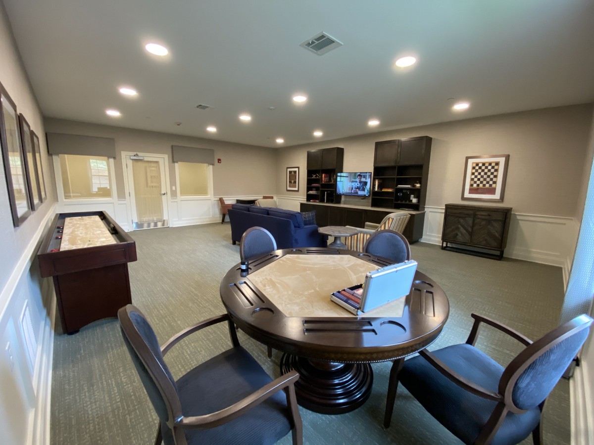 A spacious lounge area with comfortable seating, a television, and gaming tables.