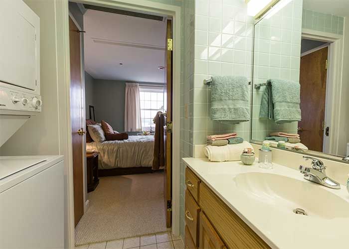 A view from a bathroom into a bedroom, featuring a sink and towels.