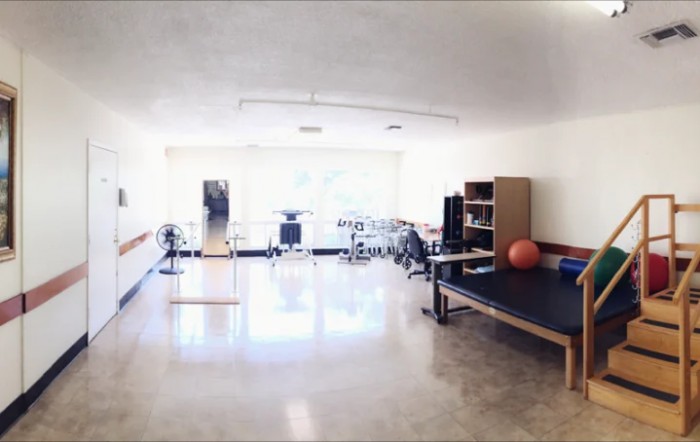 A bright rehabilitation room equipped with exercise and therapy equipment for physical therapy sessions.