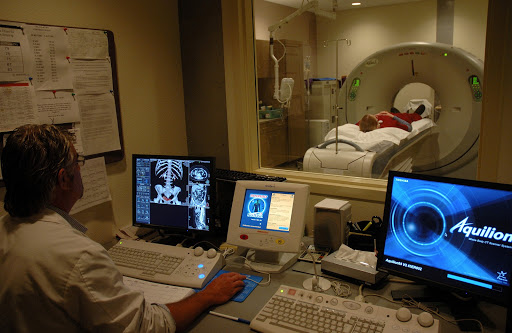 A radiology technician operates an MRI machine while monitoring a patient undergoing the scan.