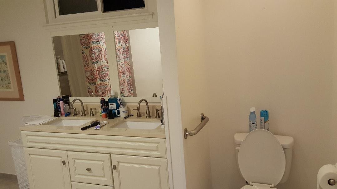 A bathroom with a dual sink vanity and a toilet.