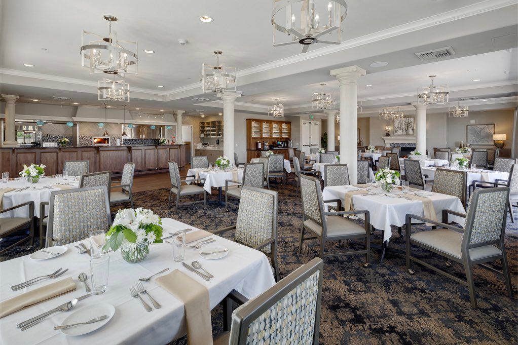 An elegant restaurant dining room with neatly arranged tables and stylish chandeliers.