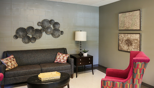 A cozy living room space featuring a stylish sofa, a modern lamp, and decorative wall art.