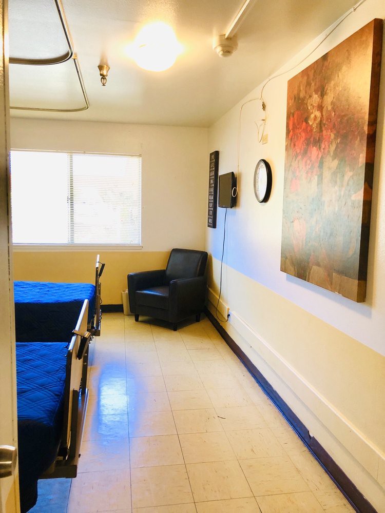 A cozy room with a bed, chair, and wall decorations.