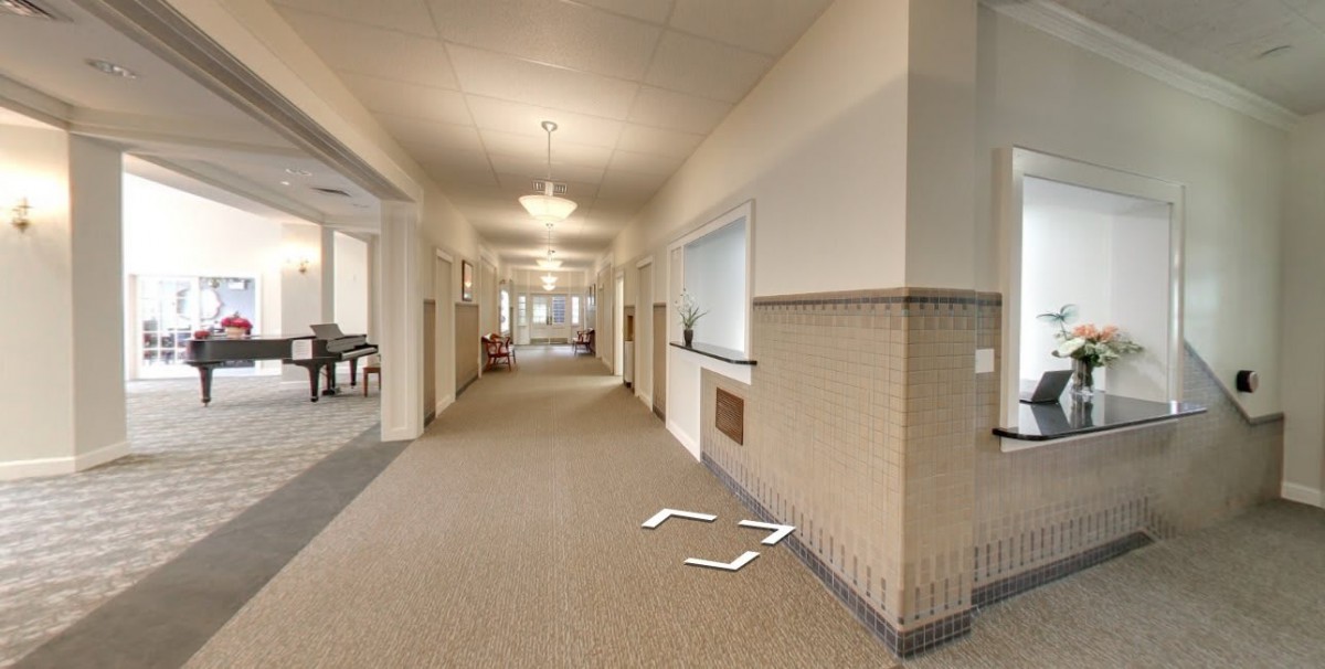 A modern hallway with carpeted floors and overhead lighting.