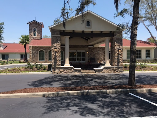 A charming building featuring a combination of stone and modern architectural elements, surrounded by trees and a well-maintained parking area.