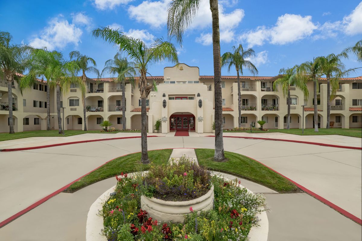 A scenic view of a Mediterranean-style building with palm trees and landscaped surroundings.