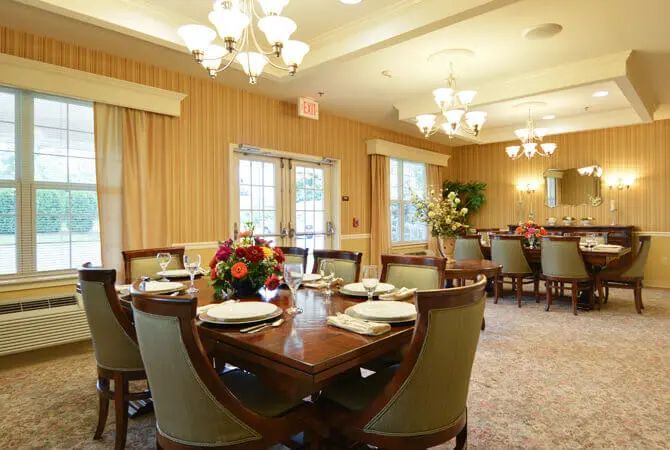 An elegantly set dining room with chandeliers and floral arrangements.