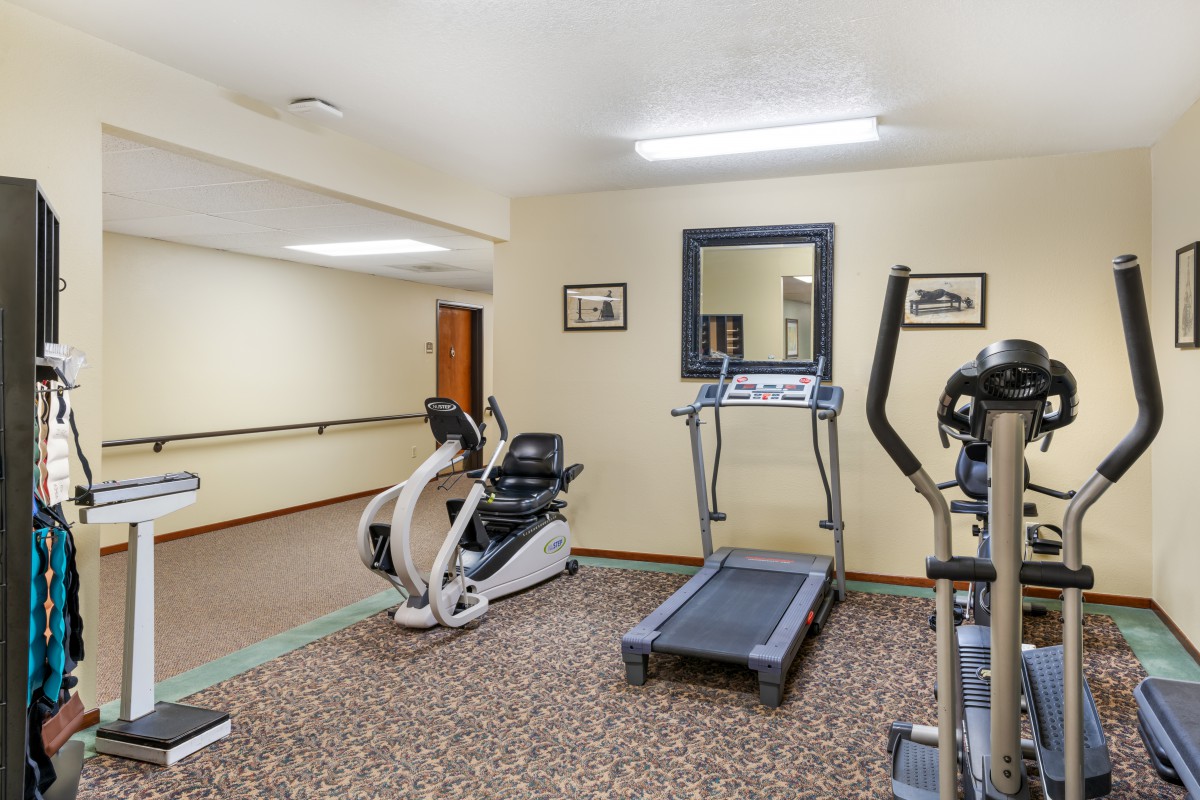 A small gym with fitness equipment including a treadmill and an exercise bike.