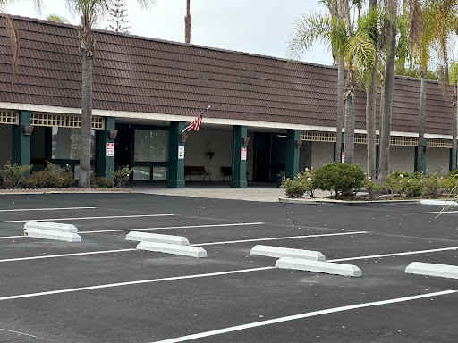 A view of a commercial building with a spacious parking lot and palm trees.