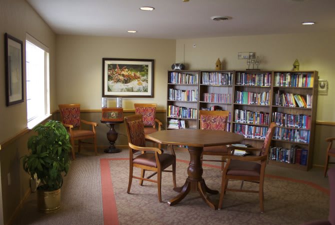 A cozy reading room with bookshelves, a round table, and comfortable chairs.