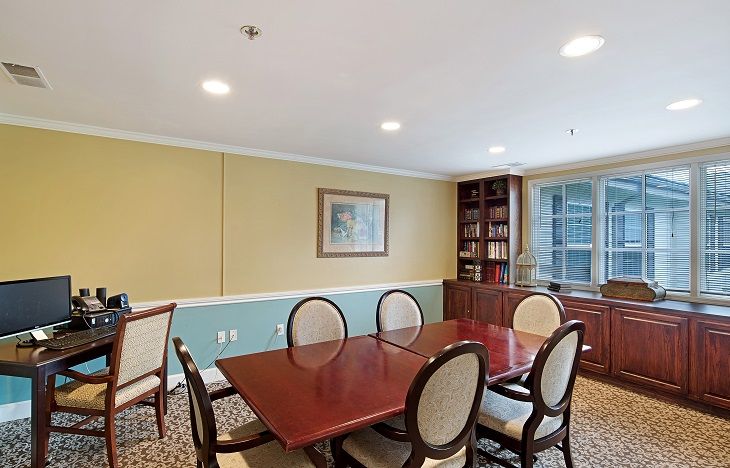 A well-appointed conference room with a large wooden table, several chairs, and a built-in bookshelf.
