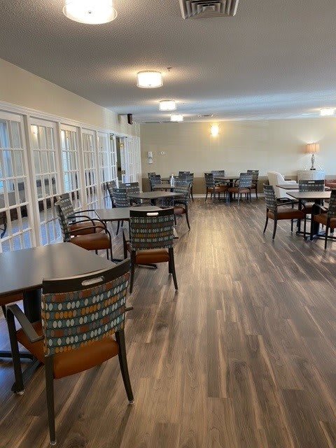 An empty dining area with neatly arranged tables and chairs on a wooden floor.