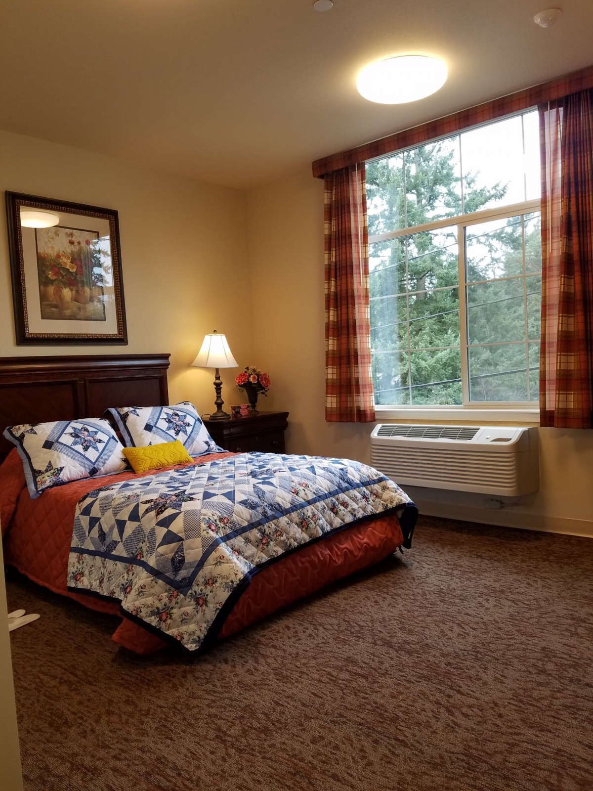 Cozy bedroom with a large window and patterned bedding.