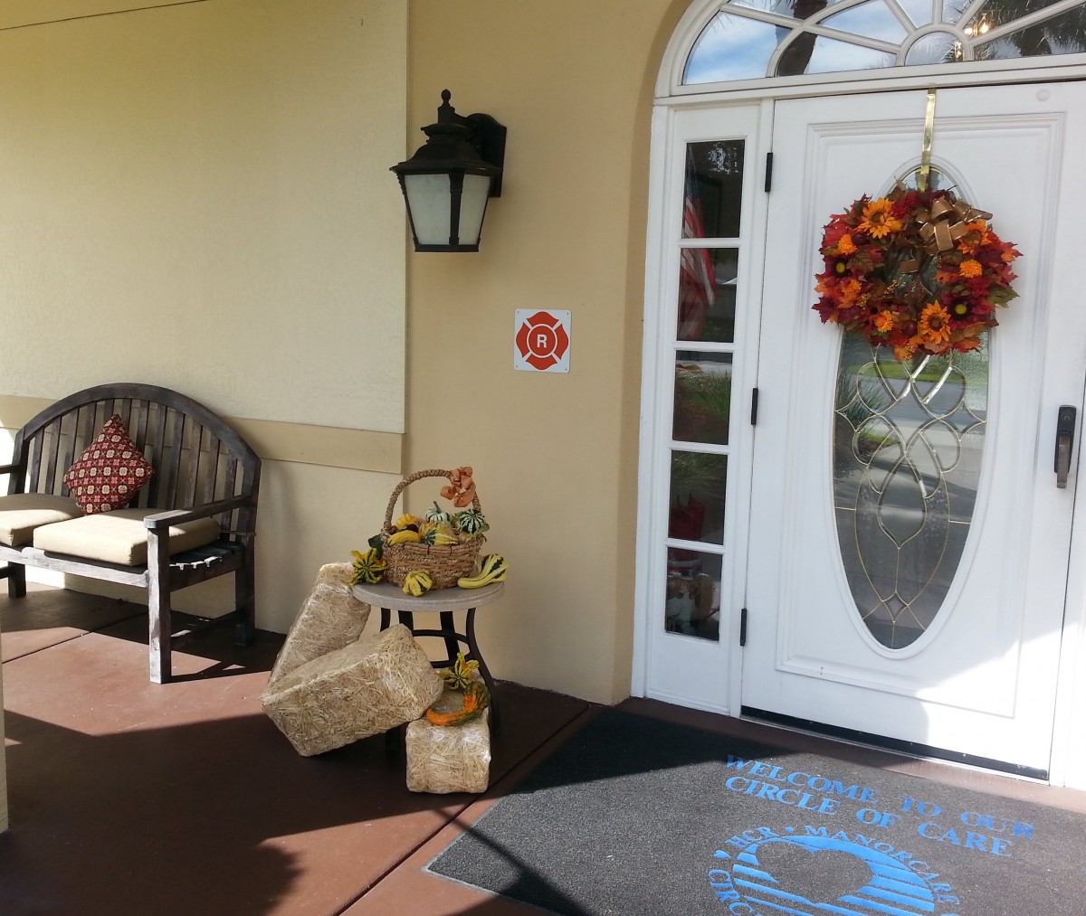A welcoming front porch decorated for autumn with a wreath, bench, and seasonal baskets.