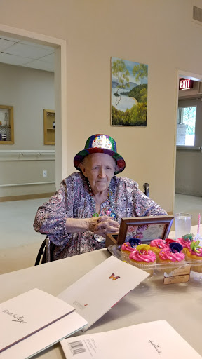 An elderly woman wearing a colorful hat enjoys a special moment during a birthday celebration.
