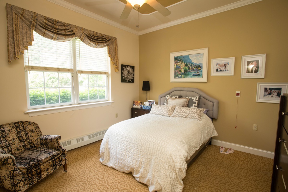 A cozy bedroom with a neatly made bed, decorated with artwork and soft lighting.