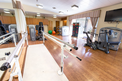 A spacious fitness and rehabilitation room featuring exercise equipment and a ballet barre.