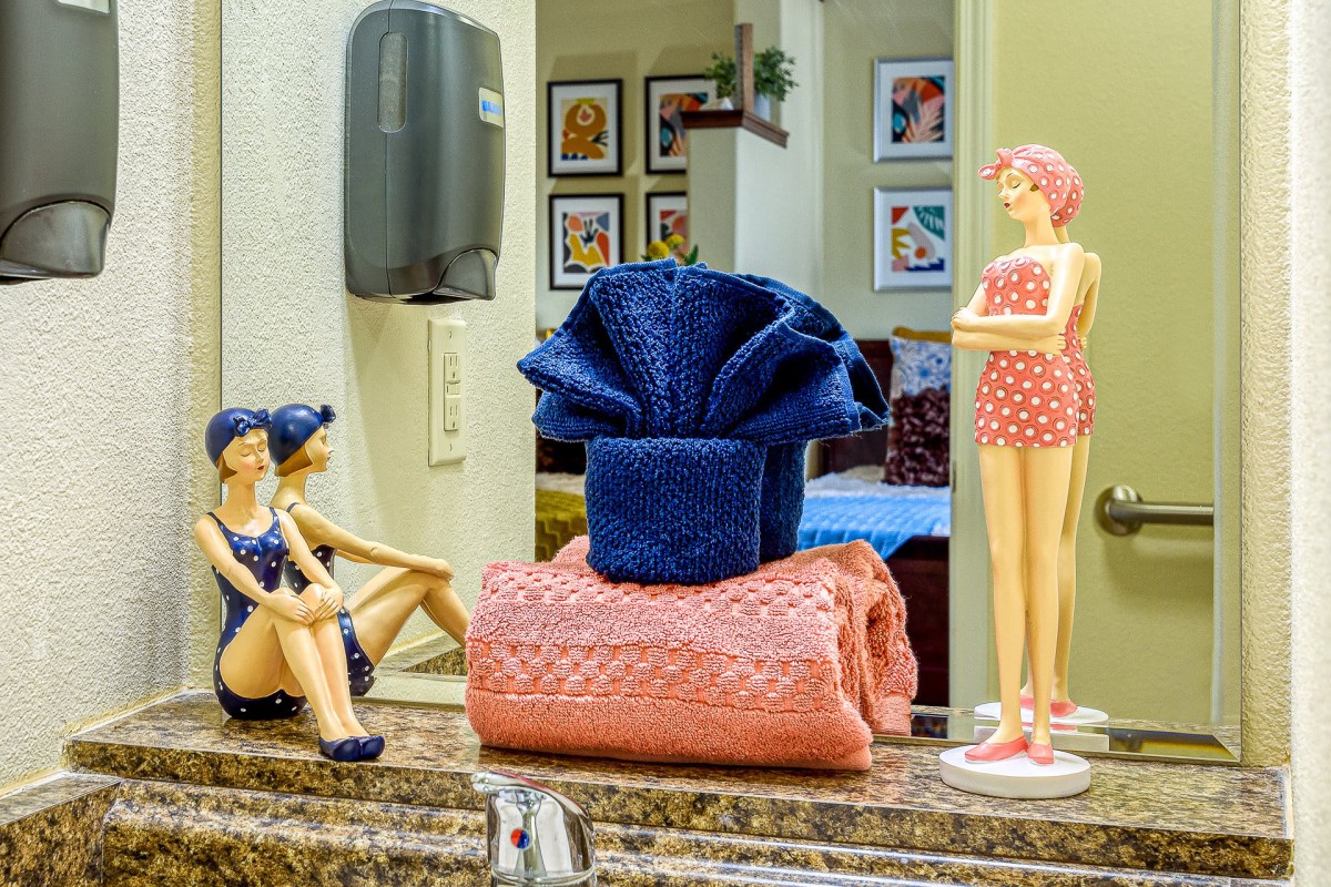 A decorated bathroom counter featuring neatly folded towels and whimsical figurines.