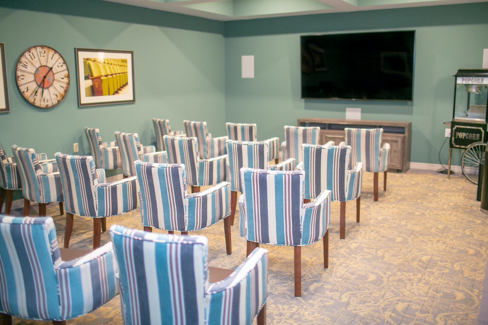A conference room with striped upholstered chairs arranged facing a large television.