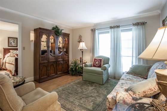A cozy living room with comfortable seating, a wooden cabinet, and natural light from large windows.