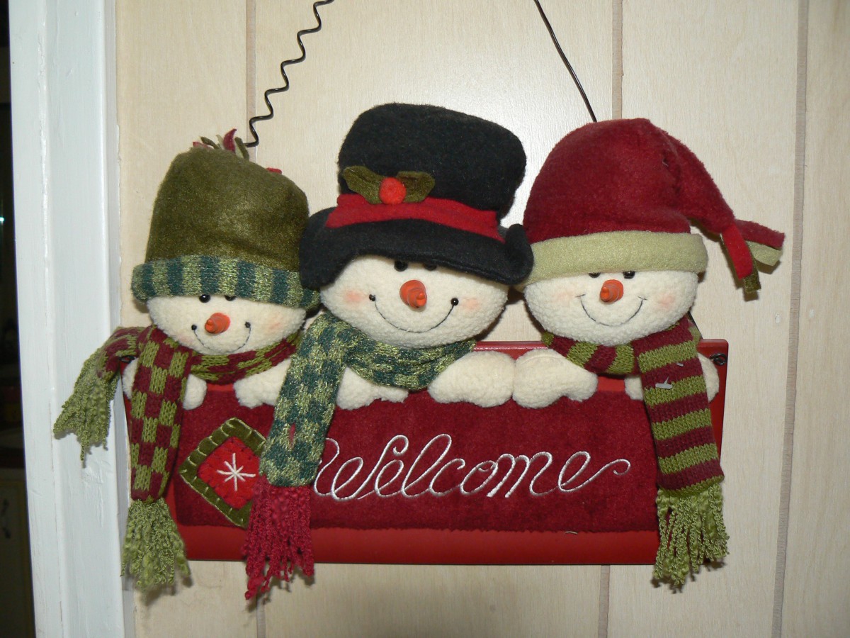 Festive hanging snowmen welcome sign for the holiday season.