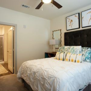 A cozy bedroom with stylish decor featuring a bed, decorative pillows, and artwork.