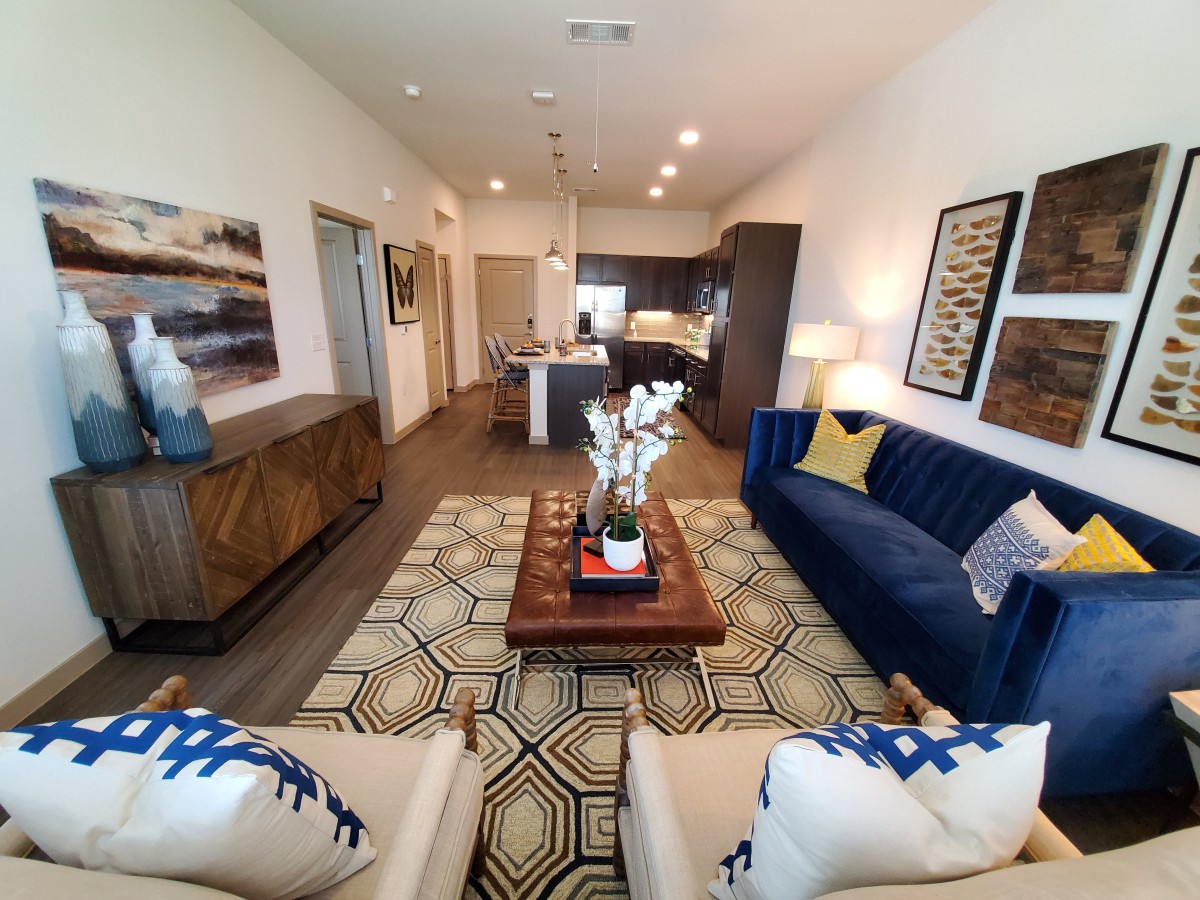 A modern living room with stylish decor, featuring a blue sofa and patterned rug.