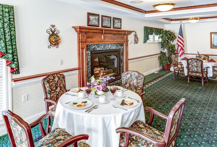 An elegantly set dining table in a cozy room with a fireplace and an American flag decoration.