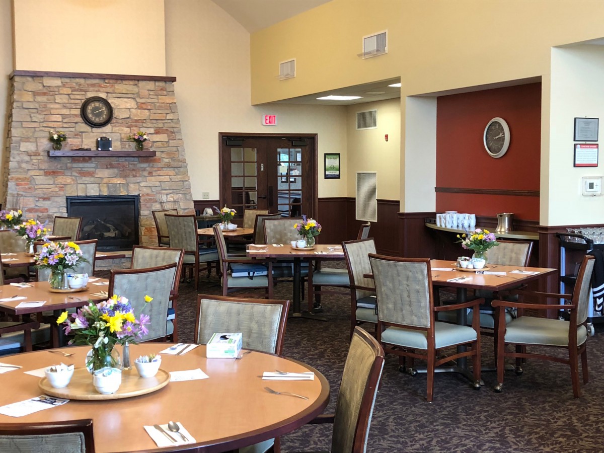 A cozy dining area with neatly arranged tables and chairs, decorated with fresh flowers.