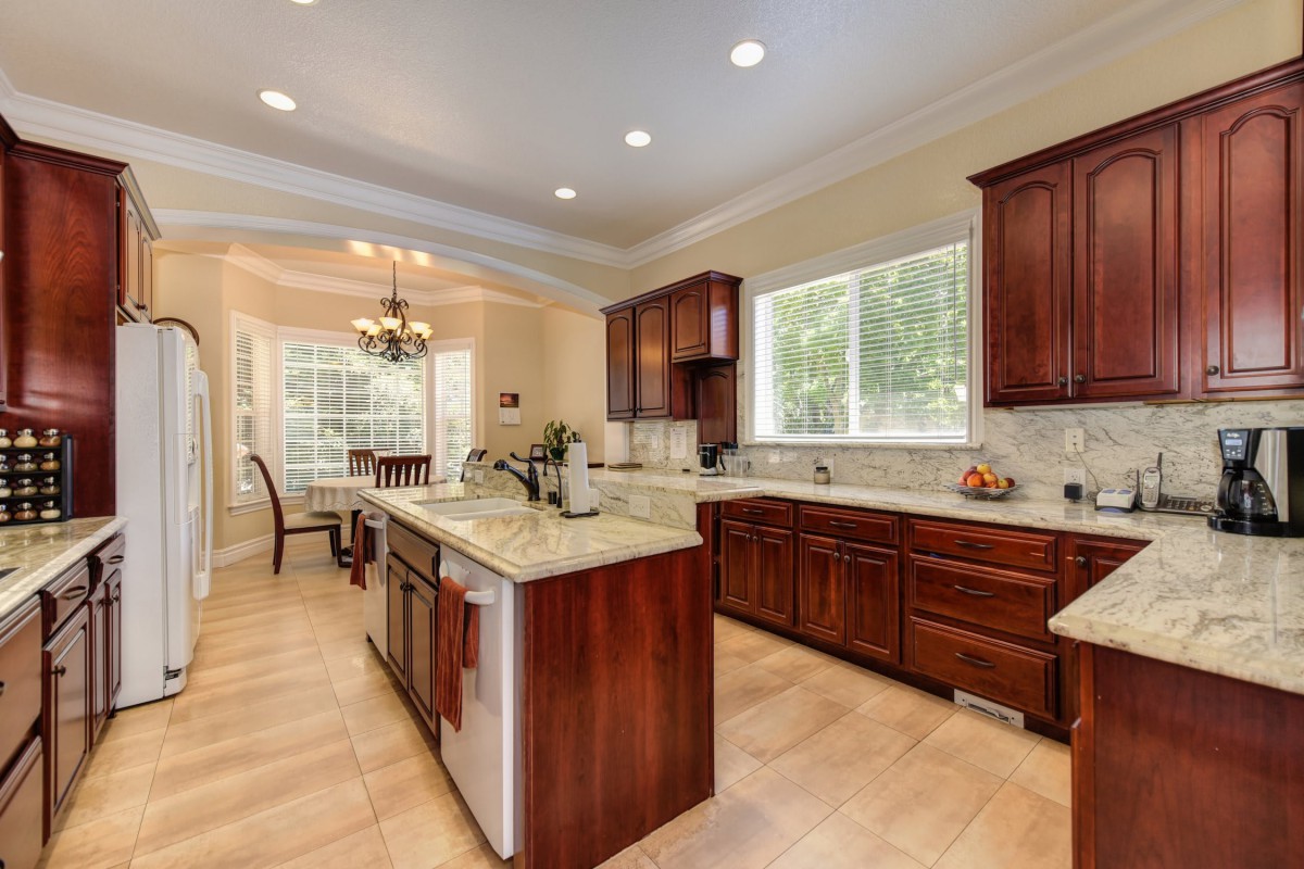 A spacious modern kitchen with wooden cabinets, a granite island, and an adjoining dining area.