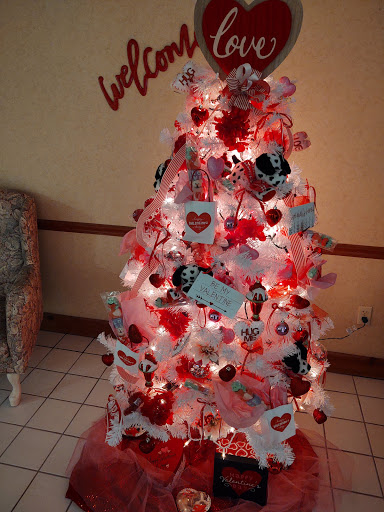 A beautifully decorated Christmas tree featuring a vibrant mix of red and pink ornaments, hearts, and lights, capturing the spirit of love and festivity.