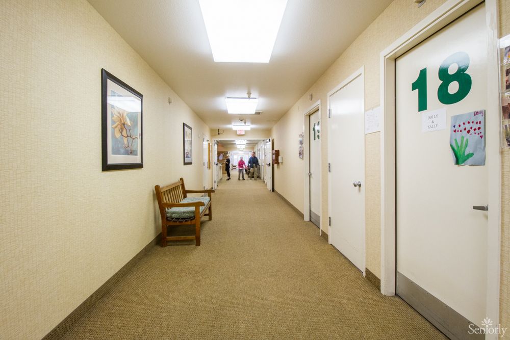 A well-lit hallway with doors on both sides and seating along the wall.