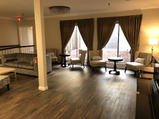 A cozy living room with sofas, chairs, and large curtained windows.