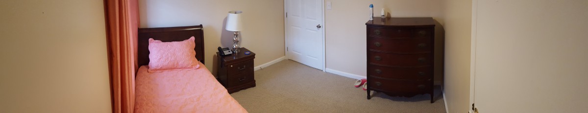 A simple room with a closed door, carpeted floor, and a nightstand.