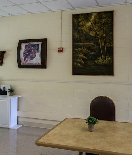 A cozy interior featuring a table and chair, complemented by artwork on the walls.