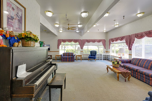 A spacious living room featuring a piano and comfortable seating, illuminated by natural light from large windows.