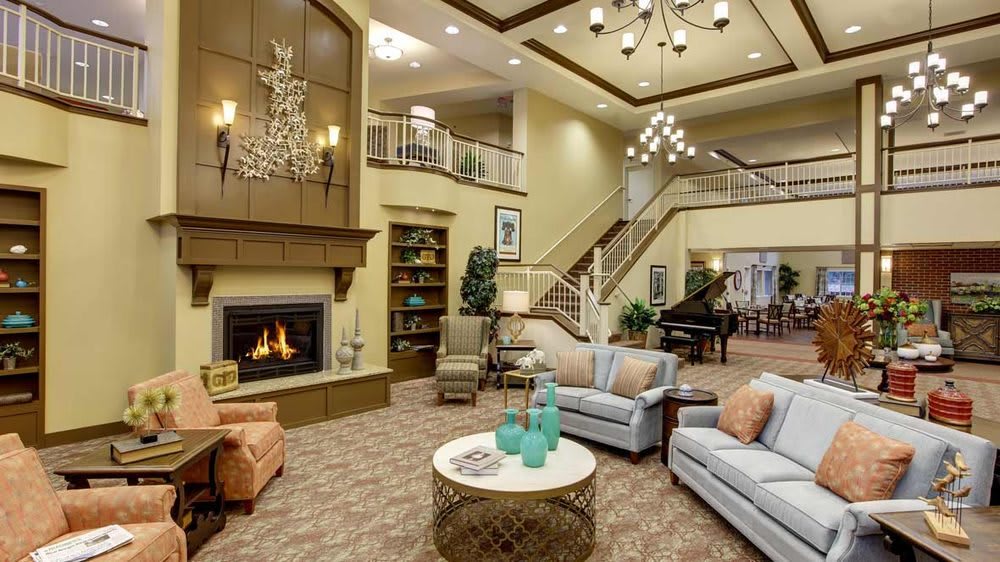 A cozy and elegantly designed living room featuring a fireplace, comfortable seating, and a grand piano.