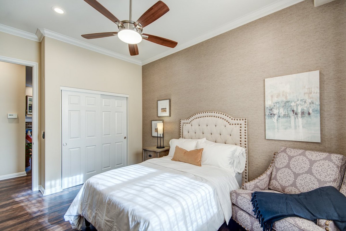 A cozy bedroom featuring a neatly made bed, ceiling fan, and stylish decor.