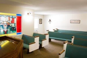 A small chapel interior with pews and colorful stained glass.