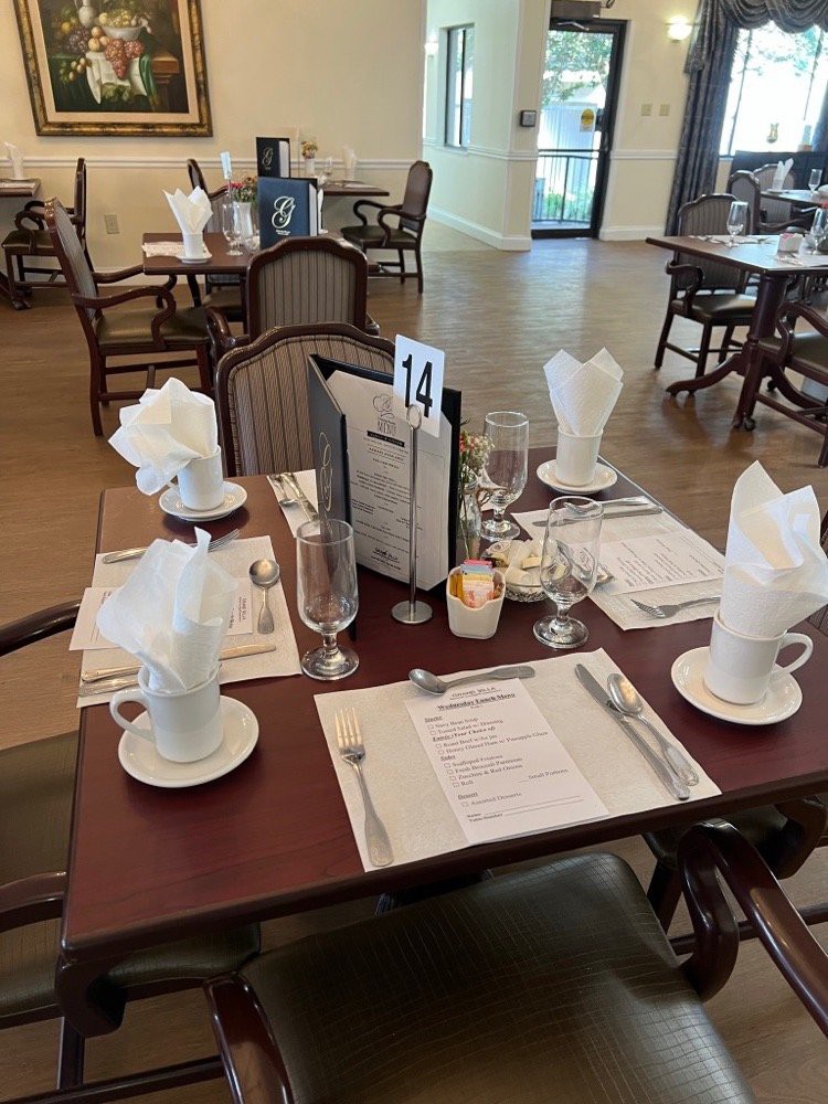 An elegantly set table in a restaurant, featuring menus, glasses, and neatly folded napkins.