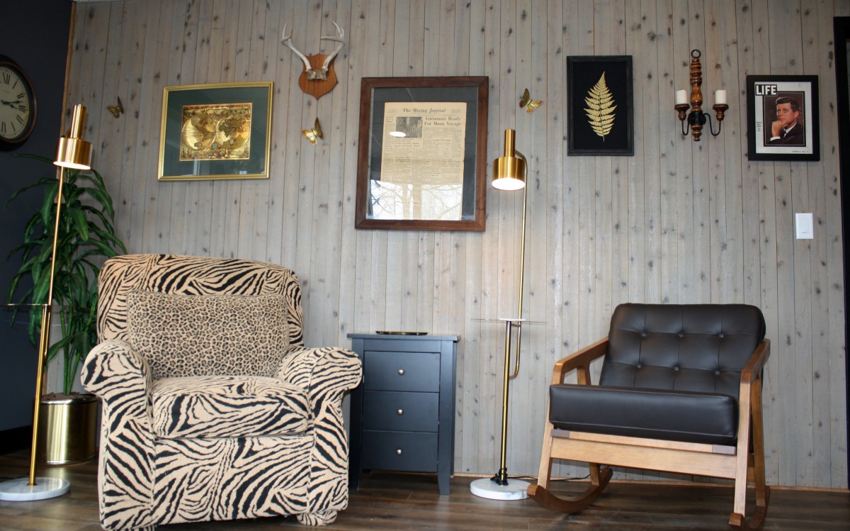 A cozy living room with eclectic decor, featuring a zebra print couch and various wall art pieces on wood paneling.