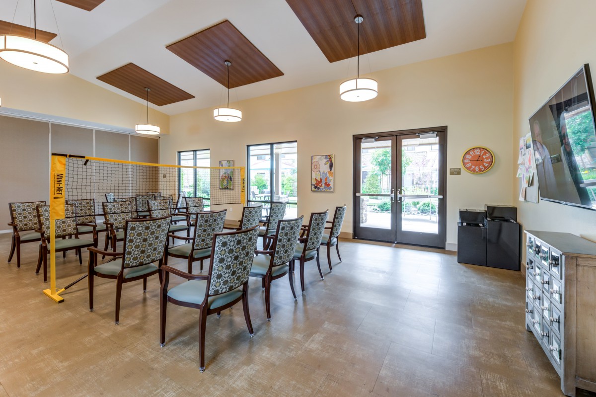 A well-lit meeting room with arranged chairs and large windows.