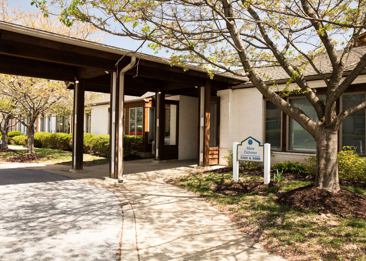 A building entrance surrounded by trees with a sign nearby.