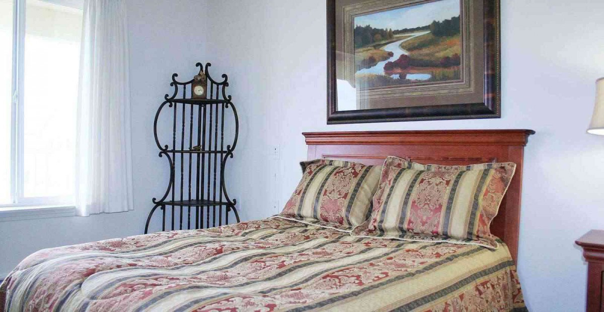 A cozy bedroom with a decorative bedspread and framed artwork on the wall.