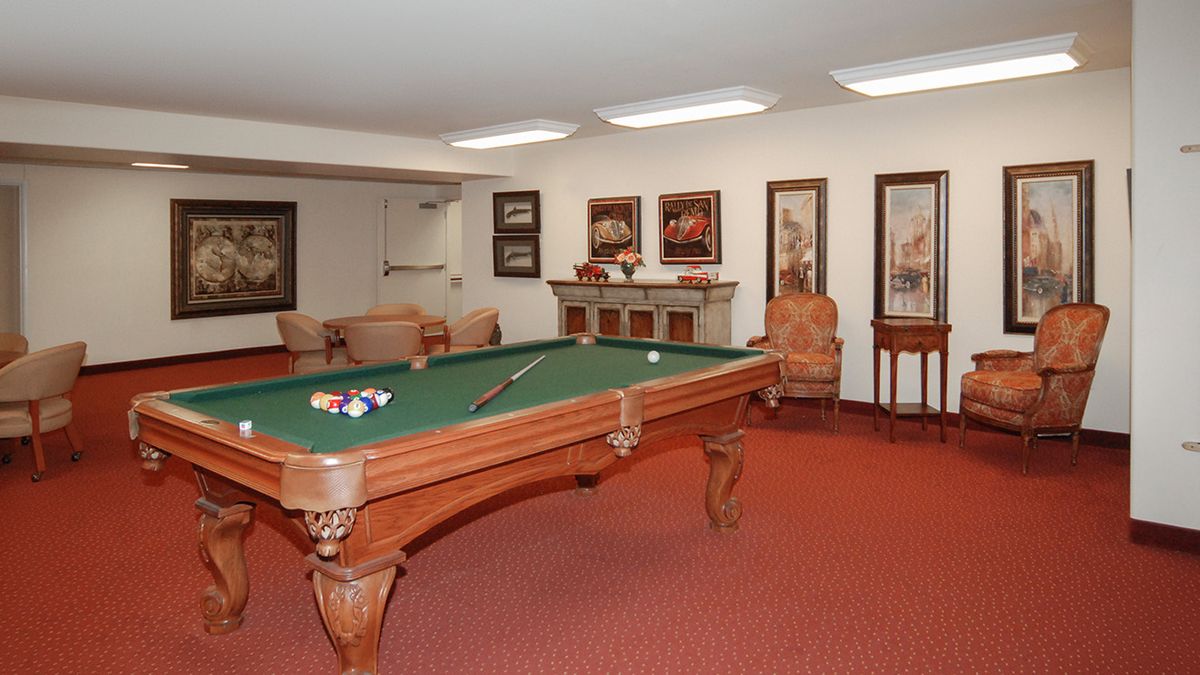 A cozy game room featuring a classic pool table surrounded by comfortable seating and decorative artwork.