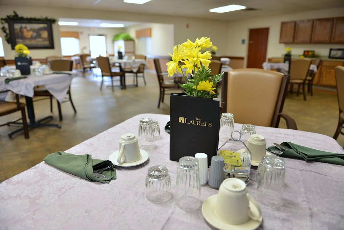 A beautifully set table in a dining room with yellow flowers as a centerpiece.